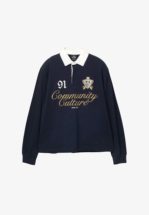 Marine langærmet polo t-shirt med hvid krave, prydet med guld broderet tekst "Community Culture" og tallet "91" samt et dekorativt våbenskjold.