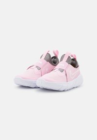 Baskets de sport roses avec une tige en maille, des sangles élastiques et une semelle blanche. Elles présentent un talon en boucle et de petits accents de logo. Texture douce.