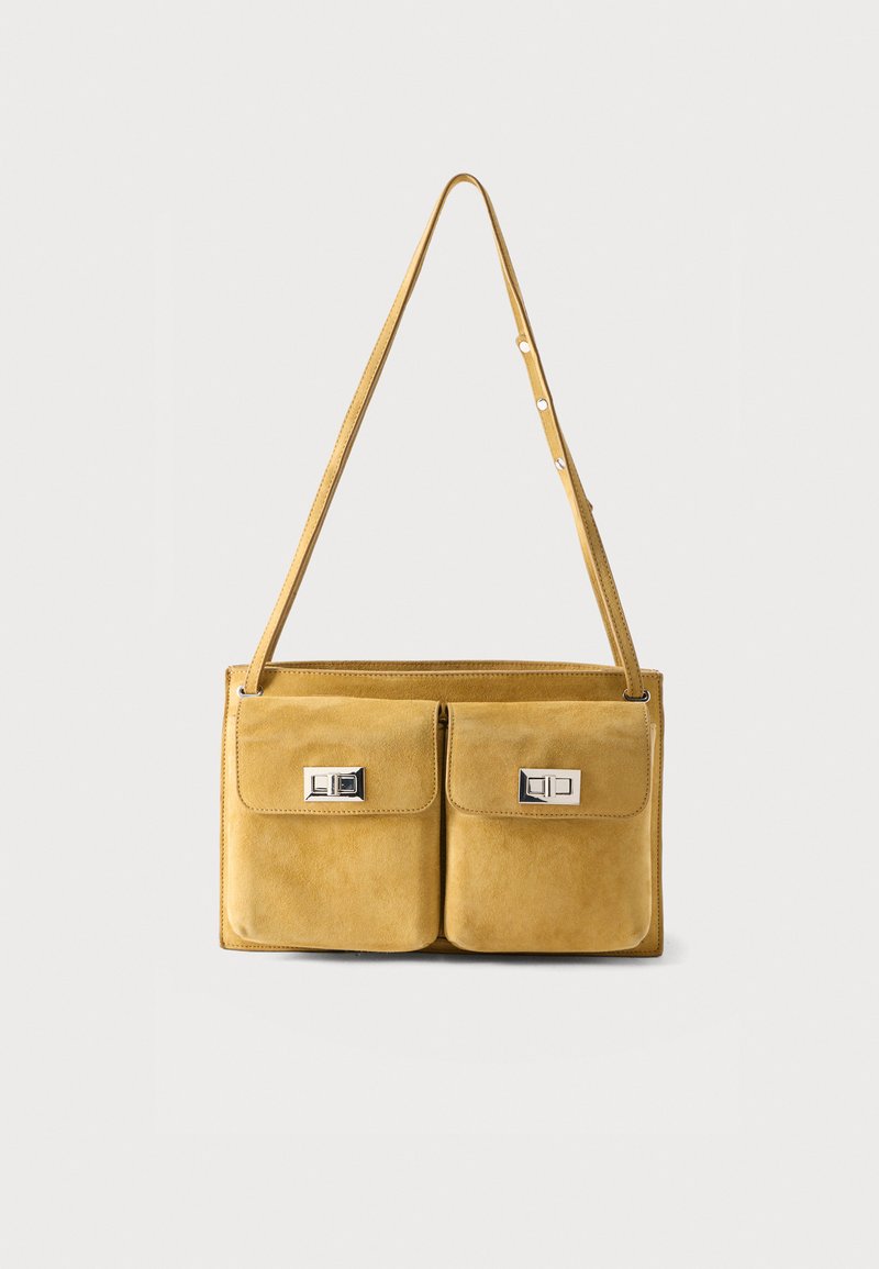 Πορτοκαλί ώχρας σουέτ τσάντα ώμου με δύο μπροστινές τσέπες με καπάκι, ορθογώνιες ασημένιες κλειδαριές περιστροφής και ρυθμιζόμενο ιμάντα.