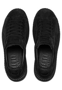 Baskets basses en suède noir avec semelles épaisses et lacets noirs, vues d'en haut, montrant des semelles intérieures marquées "FENTY".