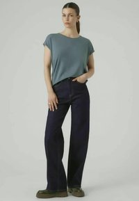 Lyseblå t-skjorte med korte ermer, kombinert med vide mørk denimbukser. Buksene har høy midje og en ren finish nederst.