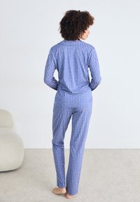 Blårandiga pyjamaser gjorda av mjukt tyg, med lång ärm och raka byxor. Ränderna växlar mellan ljusa och mörka nyanser.