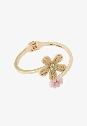 Bracelet ton doré avec fermoir à charnière, présentant une fleur tissée beige avec un centre en strass et un petit pendentif en forme de fleur rose.