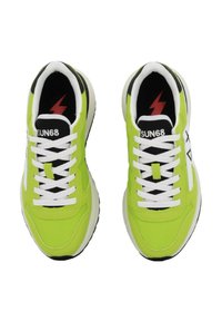 Sneakers verde neon con lacci bianchi, accenti neri e un logo a forma di fulmine sulla linguetta. Presentano una parte superiore testurizzata e una suola in gomma.