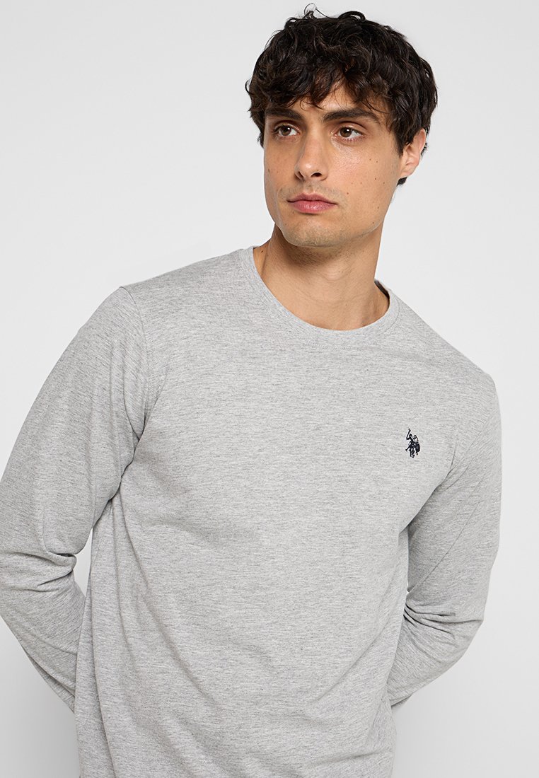 Graues Langarmshirt aus weichem Baumwollmix, mit Rundhalsausschnitt und kleinem blauen Logo auf der linken Brust. Glatte Textur und klassischer Schnitt.