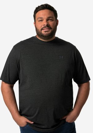 Camiseta de manga corta gris oscuro con cuello redondo y un logo sutil en el pecho. Textura suave, corte informal, combinada con jeans azules.