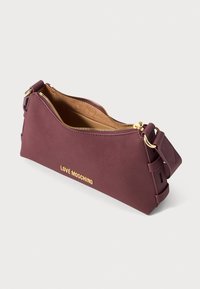 Maza bordo plecu soma ar zelta rāvējslēdzēju un "LOVE MOSCHINO" logo, ar regulējamu siksnu un daļēji atvērtu augšdaļu, kas rāda brūnu interjera apdari.