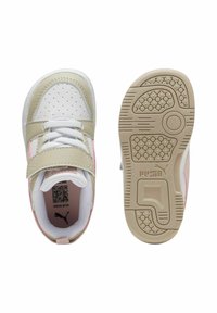 Zapatillas Puma con parte superior blanca y beige, acentos rosas, puntera perforada, y una suela de goma marrón con patrones de agarre texturizados.