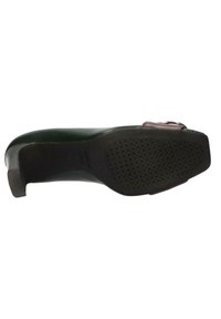 Zapato verde de cuero con puntera redondeada, tacón plano y suela texturizada negra. Presenta un acento burdeos cerca de la hebilla.