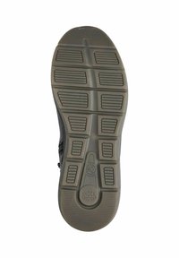 Semelle de chaussure de sport noire avec une surface en caoutchouc texturée, comportant un motif de rainures et de sections surélevées pour l'adhérence. Étiquette "Shock Absorber" visible.