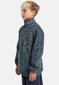 Fleece-Pullover mit hohem Kragen, der ein strukturiertes, blau-grünes Muster aufweist und einen Viertel-Reißverschluss hat. Lockerer Schnitt mit angeschnittenen Ärmeln.