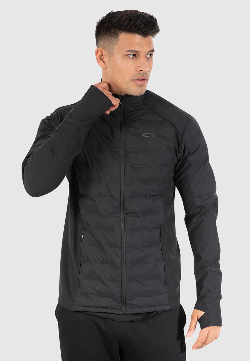 Veste isolée noire avec un devant matelassé, des manches lisses, un col haut et des poches zippées. Comprend des ouvertures pour les pouces dans les poignets.