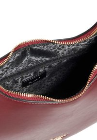 Burgundy leather handbag with a gold zipper, featuring a patterned black interior and a small zippered pocket inside.