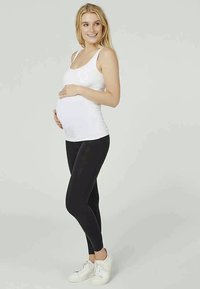 White tank top, black leggings, and white sneakers. The tank top is fitted, while leggings have a smooth texture, suitable for maternity wear.