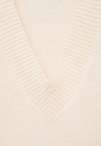 Pull en maille beige avec un design en V, doté d'une texture côtelée le long du col. Tissu doux et lisse avec une apparence légère.