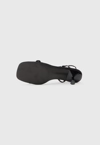 Pantof de damă cu toc înalt, de culoare neagră, cu un finisaj elegant din patent, design cu vârf deschis, curea ajustabilă și talpă din cauciuc texturat.