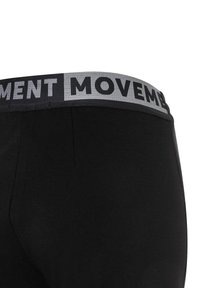 Leggings negros con una cinturilla elástica gris que lleva el texto "MOVIMIENTO" en negro. Textura suave con un diseño ajustado.