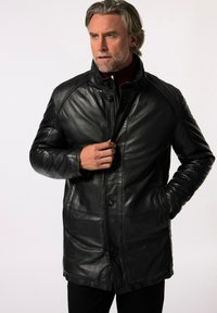 Černý kožený kabát s vysokým límcem, předním zipem a zapínáním na knoflíky. Má hladkou texturu a prošívané detaily, vhodný do chladného počasí.