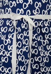 Abito navy con motivo infinito bianco, dotato di una fascia in tessuto testurizzato e un nastro bianco legato in vita. Tessuto di cotone liscio.