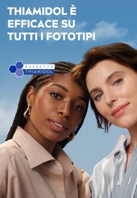 Due donne con acconciature diverse fronteggiano la macchina fotografica. Una indossa una camicia beige chiaro, l'altra una camicia a righe blu. Lo sfondo è di un blu chiaro.