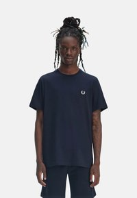 Camiseta de algodón azul marino con cuello redondo, mangas cortas y un pequeño logo bordado en blanco en el lado izquierdo del pecho. Corte relajado.