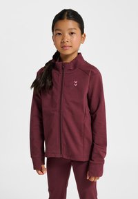 Vinröd zip-up-jacka med hög krage, långa ärmar och subtil chevronlogga i ljusrosa. Figursydd design i mjukt, texturerat tyg.