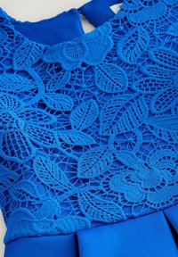 Blauwe jurk met ingewikkelde kantdetails in bladvormen, gemaakt van een textuurstof. De lijfje heeft een ronde halslijn en een gladde zoom.
