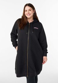 Sort quiltet hættetrøje med lynlås og hætte, med gyldne lynlåse og snore, ribbede ærmeafslutninger og et lille broderet logo.