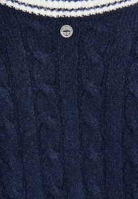 Marineblauer Strickpullover mit einem Zopfmuster und einem gerippten Halsauschnitt in Weiß und Blau gestreift. Metalllogo-Akzent mit einem Ankerdesign.
