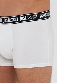 Białe bawełniane bokserki z czarnym paskiem w talii, na którym znajduje się powtarzający się biały napis "Justcavalli". Wygodny, dopasowany krój.