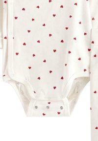 Body à manches longues en coton blanc avec des motifs de coeurs rouges éparpillés ; il présente des boutons-pressions à l'arrière pour un enfilage facile.