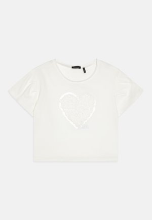 Biele skrátené tričko z mäkkej tkaniny, s dizajnom srdca z flitrov v strede a okrúhlym výstrihom. Krátke rukávy.