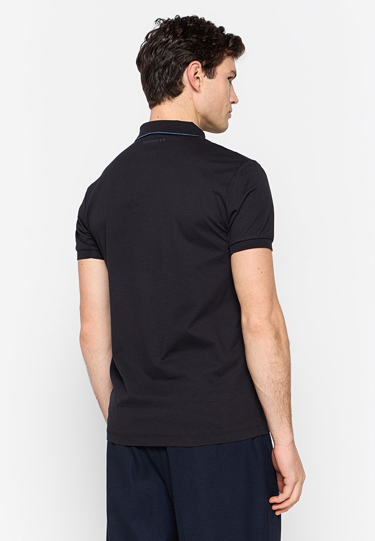 Camisa polo negra con cuello clásico, mangas cortas y un sutil detalle del logo en la parte posterior, hecha de una suave tela de algodón.