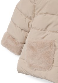 Giacca trapuntata beige con un esterno liscio, caratterizzata da una soffice tasca in pelliccia sintetica e da una cucitura texturizzata lungo le giunture.