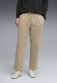 Beige sweatpants med snor i taljen, der har diskrete side sømme og et logo detalje. Båret med cremelignende træningssko.