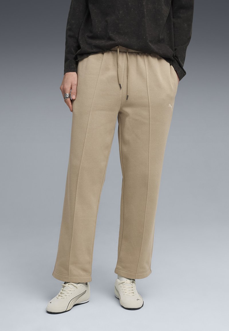 Beige sweatpants med snor i taljen, der har diskrete side sømme og et logo detalje. Båret med cremelignende træningssko.