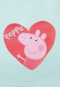 Cartone di maialino rosa all'interno di un cuore rosso su uno sfondo di tessuto azzurro chiaro, con il testo "Peppa" in bianco. Textura morbida e liscia.