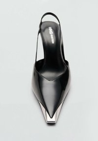 Crna lakirana kožna cipela s remenom oko pete, s oštrim vrhom i metalnim detaljem na peti. Glatka tekstura i minimalistički dizajn.