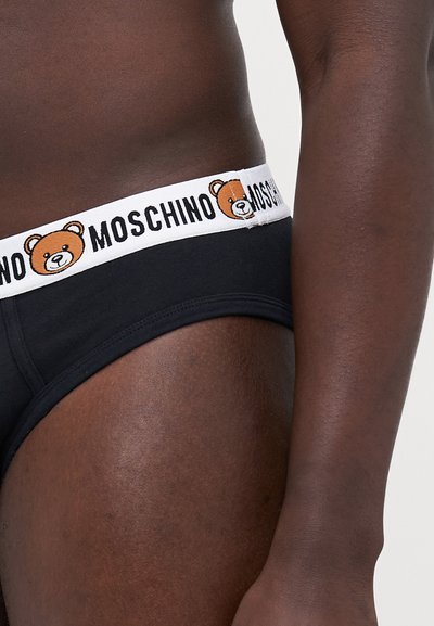 Fekete pamut alsónadrág fehér gumival, amelyen egy medve grafika és a "MOSCHINO" felirat látható. Sima textúra, testhez simuló fazon.