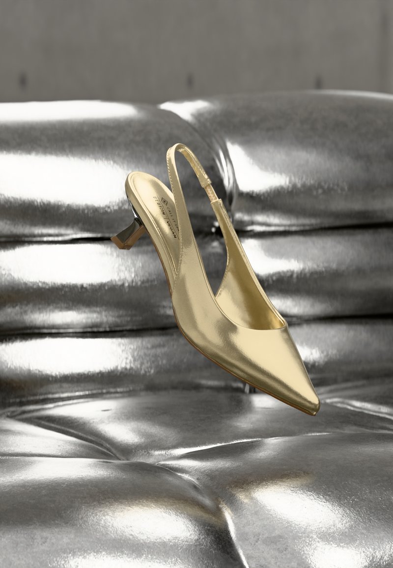 Χρυσό μεταλλικό τακούνι slingback με μυτερή μύτη, λεπτό τακούνι και λεία υφή, τοποθετημένο σε λαμπερό μεταλλικό φόντο.