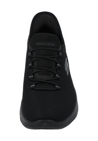 Schwarze Sportschuhe mit einem Obermaterial aus Mesh, flachem Schnürdesign, gepolstertem Schaft und Gummisohle. Mit einem Skechers-Logo an der Seite.