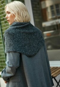 Charcoal gray wool blend shawl drapes over the shoulders of a person wearing a matching gray coat. The texture is soft and slightly fuzzy.