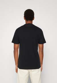 Schwarzes Baumwoll-T-Shirt mit kurzen Ärmeln und rundem Halsausschnitt, taillierter Schnitt und glatter Textur, von hinten betrachtet.