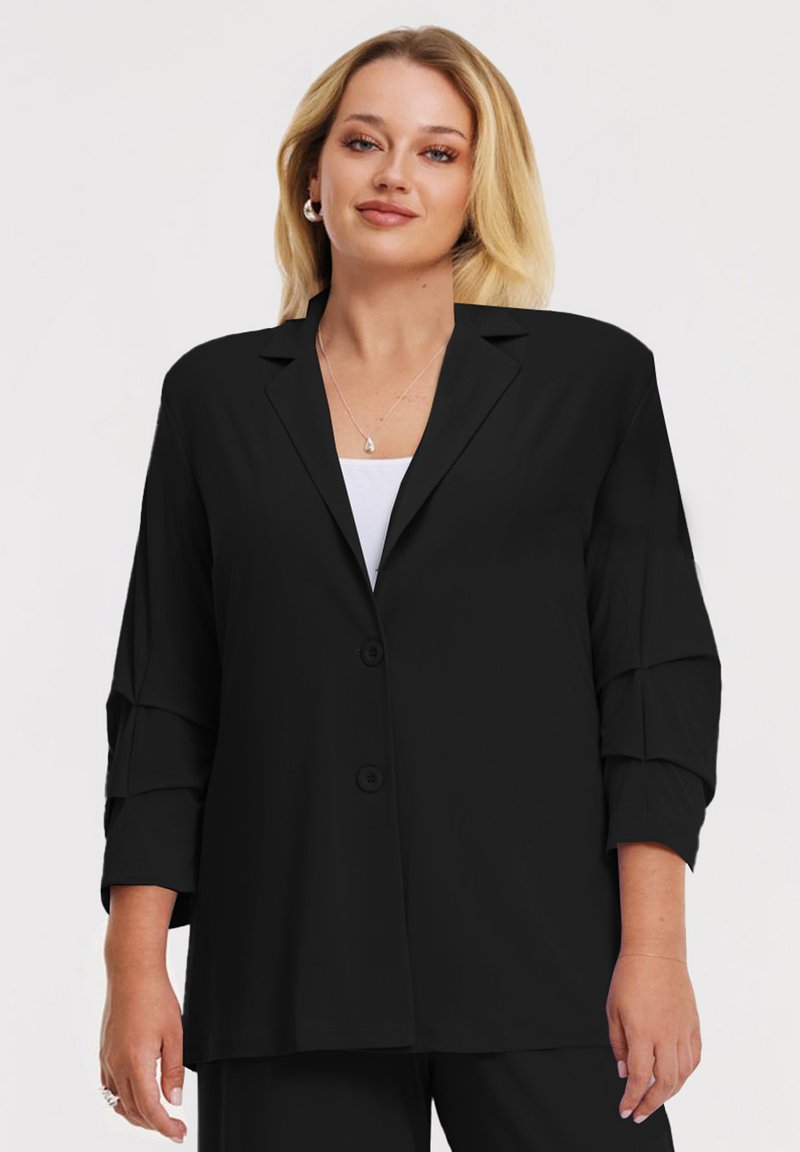Zwarte blazer met knoopsluiting, relaxed fit, driekwart mouwen en een zachte textuur. Heeft een geknoopte kraag en voorkant met knoppen.