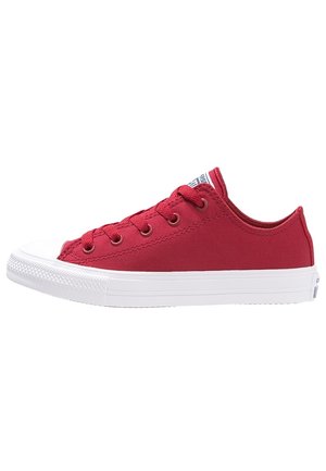 Baskets basses rouges en toile avec semelle blanche en caoutchouc et bout renforcé, lacets rouges et œillets métalliques, vues de profil.