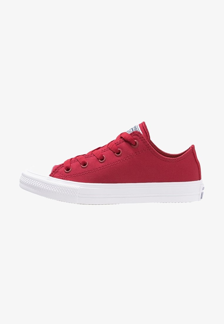 Baskets basses rouges en toile avec semelle blanche en caoutchouc et bout renforcé, lacets rouges et œillets métalliques, vues de profil.