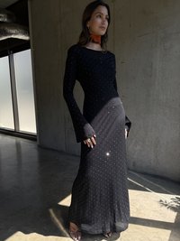 Robe noire à manches longues avec une silhouette ajustée, ornée de points argentés, dotée d'un col rond et de manches évasées.