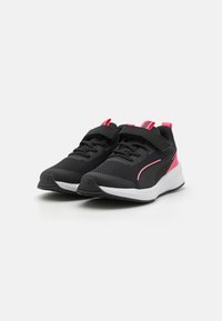 Chaussures de sport noires avec tige en maille, accents roses, sangle réglable, col rembourré et semelle extérieure en caoutchouc texturé.