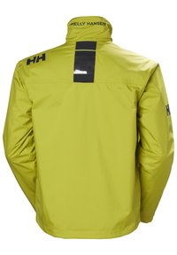Chaqueta impermeable amarilla con cuello alto, acentos de logo en negro y un panel reflectante en la parte posterior para visibilidad. Textura suave, diseño ligero.
