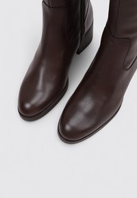Brown leather ankle boots with a smooth texture, almond-shaped toes, side zipper, and low block heels.